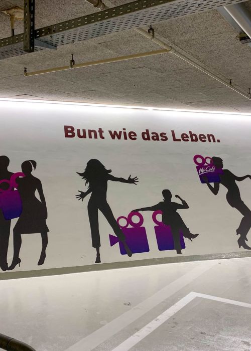 Digitaldruck auf Folie von Personen in überdimensionaler Grösse. Aufgeklebt an Wand für die Signaletik im Shoppingcenter.